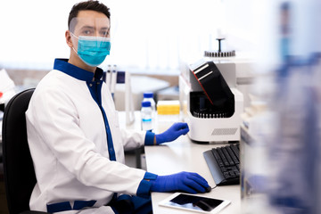 Researcher in protective medical mask working in science lab