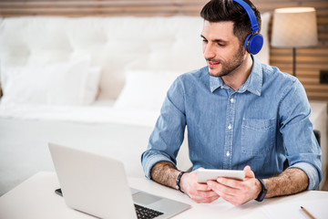 Cheerful guy in earphones and gadgets at home stock photo
