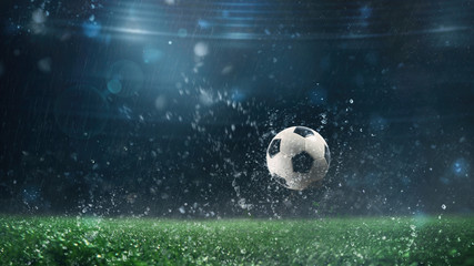 Close up of a soccer ball rolling on the playing field on a rainy night