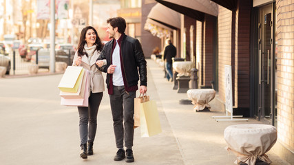 Beautiful young loving couple walking carrying shopping bags