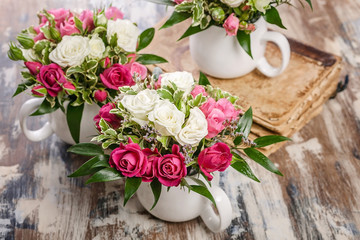 Close-up arrangement of flowers. Beautiful handmade bouquet of roses and greenery in a large cup on a rustic background. Great gift for Mothers Day, March 8 or Valentines Day