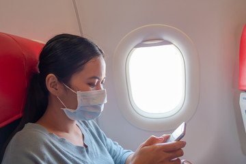 Asian girl use a protection mask for coronavirus or covid 19 in airport. Thai lady playing with her...