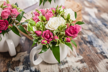 Close-up arrangement of flowers. Beautiful handmade bouquet of roses and greenery in a large cup on...