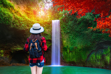Asian woman at amazing Tibumana Waterfall Bali - the best cascade in Indonesia.