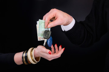 Men's hand giving to  woman's hand euro banknotes and car keys