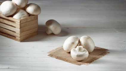 fresh uncooked champignon mushrooms on a white wooden table