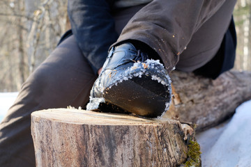 a man with blond hair in a white shirt and black coat walks in the woods in winter