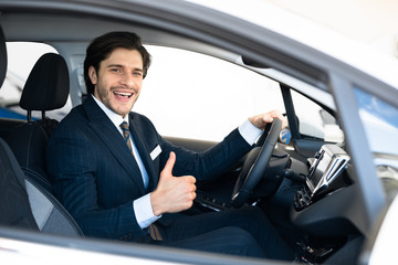 Businessman Buying Car Gesturing Thumbs-Up In Driver's Seat