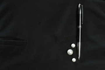 black luxury metal pen with white jewelry pearl on  black fabric business background