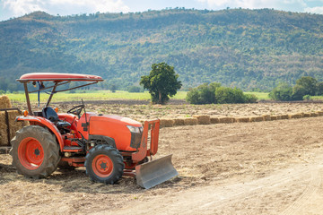 Fototapeta premium tractor in agriculture field with mountain and blue sky