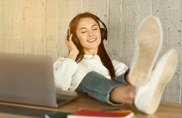 Freelance girl enjoys music in headphones, sun flare