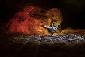 Lamp of wishes concept. Antique Aladdin arabian nights genie style oil lamp with soft light white smoke, Dark background.