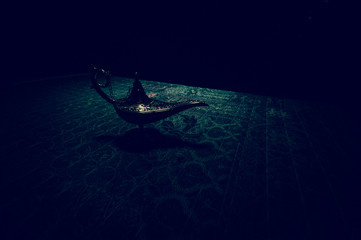 Lamp of wishes concept. Antique Aladdin arabian nights genie style oil lamp with soft light white...
