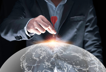 Businessman hand holding and trowing red dart to target board on black background and world map...