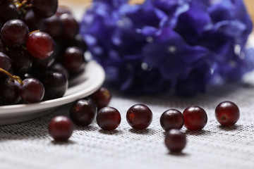Red grape in a plate with flowers on a background.