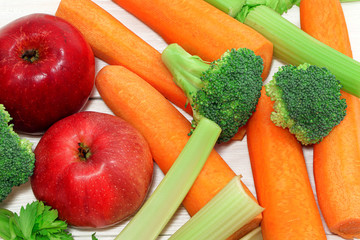 Fresh vegetables and fruits on a wooden table. Healthy, vegetarian food. Natural vitamins. Carrot, broccoli, apples and celery. Vegetables on a tray. Flat lay.