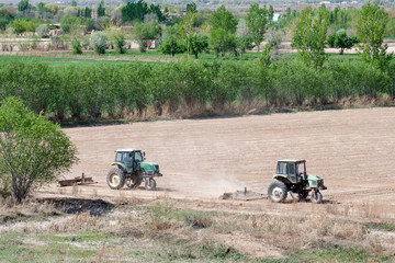 Two tractors on the field doing agricultural work. Karakalpakstan, Uzbekistan, Central Asia.