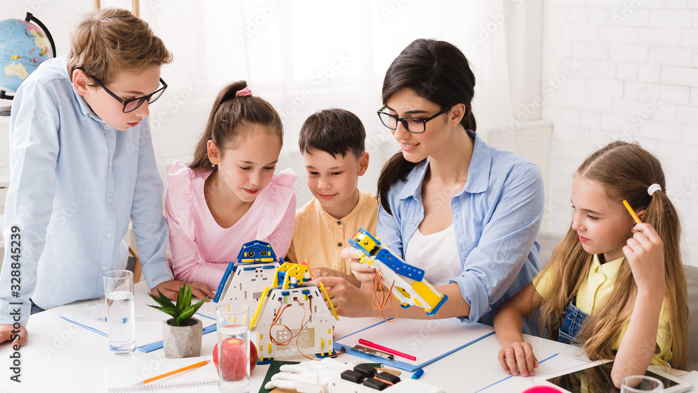 Poster Little technicians working together with teacher in robotics class