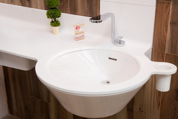 modern steel faucet with white ceramic washbasin with countertop and glass in the bathroom with tile on the wall wooden texture.