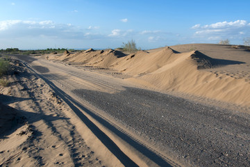 Nature conquers civilization. Sand-covered road in the middle of nowhere. Kyzylkum desert, Uzbekistan, Central Asia.