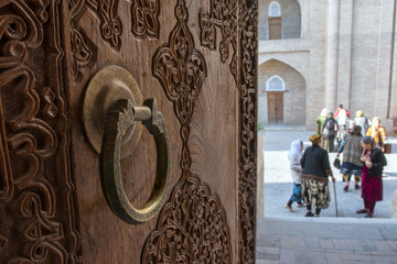Decoration detail of Pahlavon Mahmud mausoleum. Old wooden door with metal handle and carving. ...