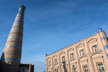 Islam Khoja Minaret (symbol of the city) and former russian school building. Khiva, Uzbekistan, Central Asia.