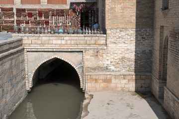 Water channel in old town and some traditional uzbek souvenirs. Bukhara; Uzbekistan, Central Asia.