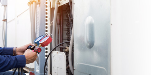 Technician is checking the air conditioner, checking the refrigerant pressure.