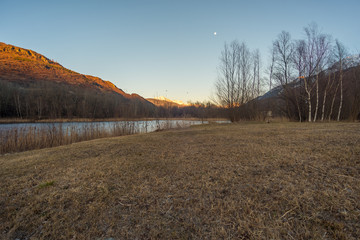 Italian lake and trees on sunset, montains with snow on background