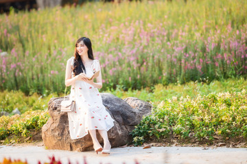 Asia beautiful woman sitting on stone and working receive orders from internet in garden.