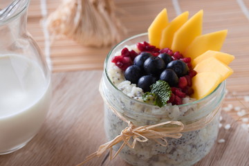 Chia Milchreis im glas mit bastschleife, angerichtet mit mango, blaubeeren, granatapfelkernen und...