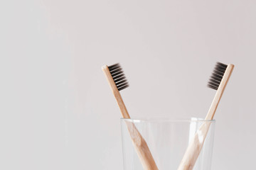 Stylish eco friendly natural bamboo toothbrushes in a glass against white background.