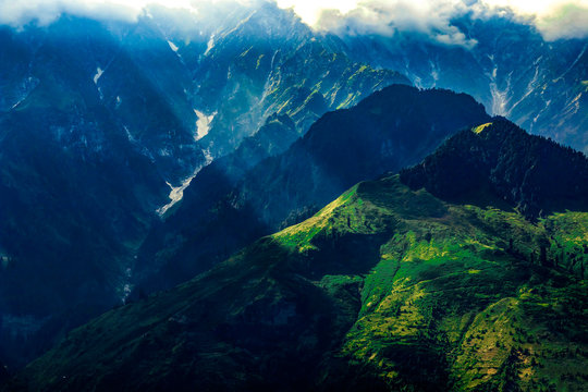 Sunbeams on the mountains with cloudy skies and deep shaded valleys in the background - taken near Brighu Lake, Himachal Pradesh, India