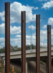 Fototapeta premium Four Steel Beams Poking into the Sky by a bridge