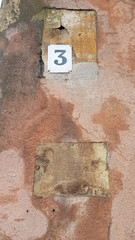 Old sign on the wall. Antique white nameplate with figure of three on grunge wall background....