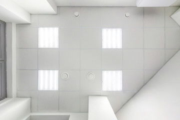 cassette suspended ceiling with square halogen spots lamps and drywall construction in empty room in apartment or house. Stretch ceiling white and complex shape. Looking up view - obrazy, fototapety, plakaty