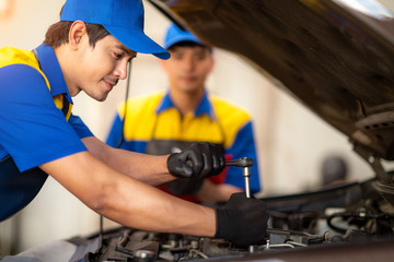Male mechanic using socket wrench while working on car engine