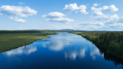 River with blue sky and clouds reflected in water in summer day. Lapland. 