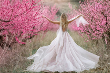 Unrecognizable woman in dress. Woman in a luxurious lace dress in the garden with flowering trees