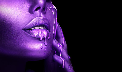 Abstract Violet makeup, Lipstick dripping. Purple Paint drops on sexy lips, face. Lipgloss drops, Liquid drops on beautiful model girl's mouth, creative make-up. Beauty woman face makeup close up