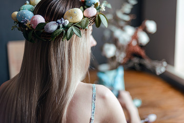 woman in easter wreath at the table with easter eggs