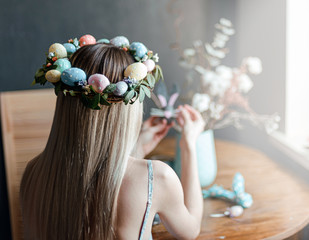 woman in easter wreath at the table with easter eggs