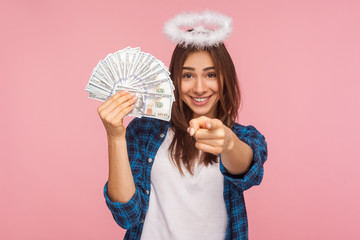 You may become rich! Portrait of happy lucky angelic girl with halo over head holding money and...