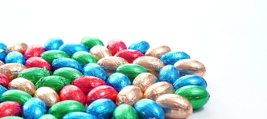 Fototapeta na wymiar Close-up of pile of colorful candy Easter eggs wrapped in colored foil. colorful candies on white background