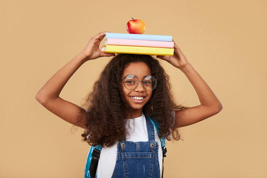 Smart black schoolgirl with textbooks and apple