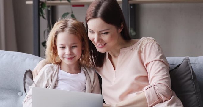 Excited young mother and kid girl look at laptop computer screen feel winners. Amazed mom with child daughter watching online game winning shopping sale discount. Family ecommerce success concept