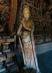 Obraz premium Wood carving of bodhisatta statue. Standing Avalokitesvara sculpture. Finest chinese art at Shuanglin Temple (or Zhongdu Temple), outskirts Pingyao Old City, Shanxi province, China
