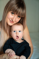 baby in black clothes yawns in the arms of mother.