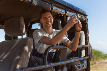 Young man taking pictures from a safari vehicle in a natural park in sri lanka © NDStock