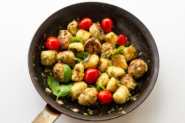 Gnocchi and chicken meatballs with pesto sauce, basil, tomatoes and nuts
